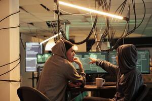 Cybercrime, hackers planning ransomware attack, hacking server, stealing data, discussing illegal malware code. Scammers cracking computer system password at night time, information leak photo