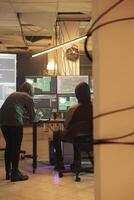Team of people talking about getting illegal access into government database, working on cracking firewall encryption at night. Spies hacking computer system together, stealing data. photo