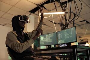 Hacker breaking into databse in vr glasses, spyware coding experience, african american man cracking computer system password in metaverse. Cybercrime, internet criminal developing malware photo