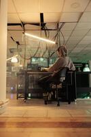 Asian IT specialist planting anonymous attack on government network, creating malware to access sensitive information on database. Young man using muliple monitors at night time. photo