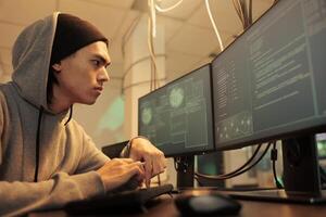 Male hacker trying to break into government network, coding computer virus on database late at night. Young spy planning data breach to hack computer system, stealing sensitive information. photo