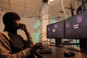 IT specialist cracking firewall encryption and accessing database server, stealing personal information and passwords. Young thief working on spyware, planting trojan virus on pc. photo