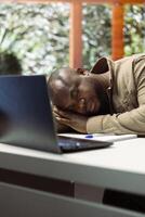 Administrator financial advisor falling asleep while he works from home, dealing with burnout and stress from online business operations. Entrepreneur takes a nap feeling exhausted. photo