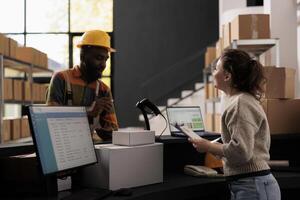 Diverse stockroom workers standing at counter desk, discussing merchandise inventory report in warehouse. Storage room employees working at customers orders checking shipping details on computer photo