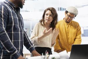 Corporate clients and their real estate agent engage in a detailed planning session, discussing the layout and design of a new office space based on blueprints. Office tour for relocation. photo