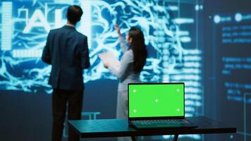 Teamworking AI technicians using green screen laptop for business data analysis. Team of IT experts works on mockup notebook to automatize tasks using artificial intelligence, camera A photo