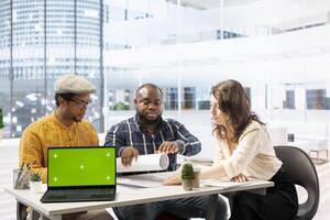 Clients negotiating with the realtor next to isolated copy space on laptop, examining layout and blueprints for a new high class office space. Business people investing in property with financier. photo