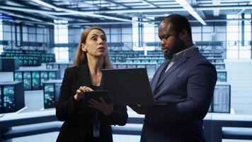 Manager in data center supervising worker running error checking utilities to fix errors. Supervisor in server farm overseeing engineer repairing network issues affecting rigs performance, camera A photo