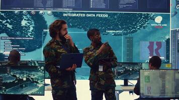 Diverse team of infantry unit leader and commander gather intelligence via radar surveillance, examine a world map to ensure national safety. Officers operating in mission control center. Camera B. photo