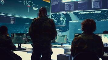 Commander and his crew operating radar systems via CCTV and satellite to detect and track enemy aircraft or missiles. Military officer uses big screen in control center to guarantee safety. Camera B. photo