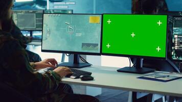 Army officer uses satellite radar footage and a greenscreen in military command post, working to gather intelligence and detect enemy ships. Commander operator at government agency. Camera A. photo
