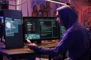 Young asian hacker holding ssd with virus to break into online server and steal data. Internet criminal using disc with ransomware for cracking password in abandoned warehouse photo