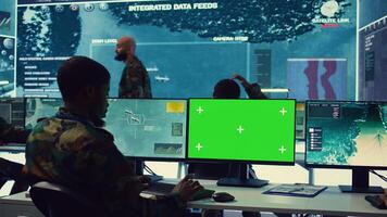 Private monitors national guard activity with military CCTV satellite system, working with a greenscreen display on pc in command center. IT reconnaissance operator tracking ships. Camera B. photo