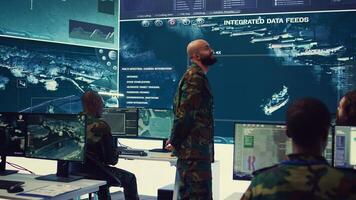 Commander managing cybersecurity measures to protect federal data from enemy breaches, working with his crew from a control center military base. Army officer ensures national safety. Camera B. photo