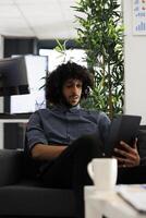 Arab business professional monitoring project analytics on digital tablet. Young company executive manager planning strategy while typing on portable device in start up office photo