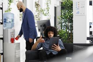 Start up company employee explaining project strategy to coworkers in conference on digital tablet. Unicorn business entrepreneur discussing financial presentation in videocall photo