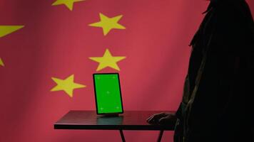 Chinese engineer uses green screen tablet to make fake accounts on social media promoting communist ideology. Technician doing cybersecurity job for CCP government with mockup device, camera B photo