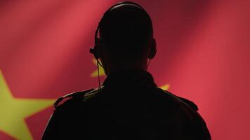 Military dispatcher working for Chinese Communist Party providing informations for troops using headset. Radio communications operator isolated over China flag background coordinating troops, camera A photo