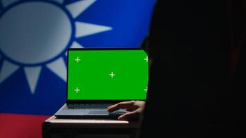 Taiwanese insurgent using military tech on green screen laptop to identify threats from enemies. Taiwan freedom fighter using software on mockup notebook to relay info to war front lines, camera A photo