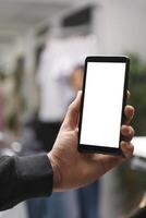 Shopping center boutique customer using smartphone blank digital display and checking sale on online website. Man hand holding mobile phone with empty screen in store closeup photo