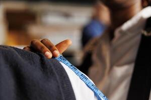 Extreme close up of thorough shoulder measuring process done in exclusive upscale atelier shop by professional suitmaker. Methodical tailor calculating perfect fit size for client photo