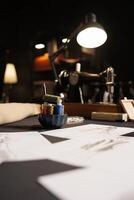 Table full of fashion designs on paper and sewing instruments in tailoring studio. Professional atelier shop workspace with sketch drawings, thread spools, sewing machine photo