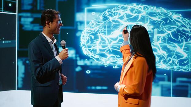 Presenter and guest chatting during AI summit discussion panel bringing together tech companies, exploring latest developments in artificial intelligence industry and emerging technologies, camera A photo