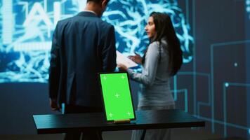 Engineers use green screen tablet and AI neural networks modeled after human brain to solve complex problems. Workers using artificial intelligence and mockup device to look at company data, camera A photo