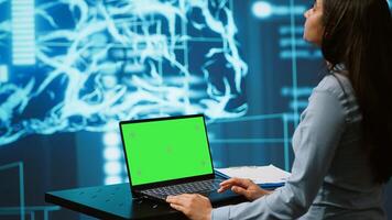 Startup employee looking over charts, using AI software on green screen laptop to take data driven decisions. Indian woman developing innovative artificial intelligence solutions for company, camera A photo