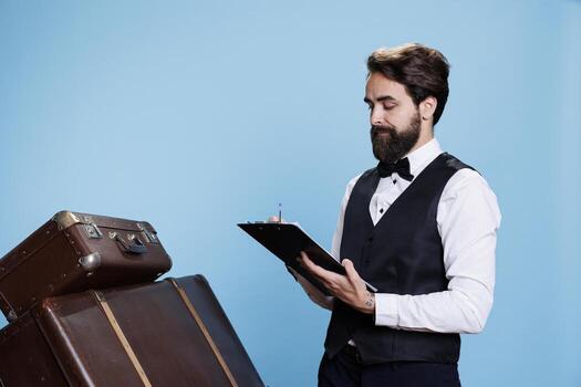 Hotel concierge takes notes on papers to keep evidence of guests, verifying bulletpoints on log register. Employee in formal attire reading and reviewing archive records of reservations in studio. photo