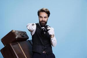 Bellhop celebrates videogames win in studio, gaming posing with remote controller and being pleased about winning online gaming play. Confident doorman having fun with competition. photo
