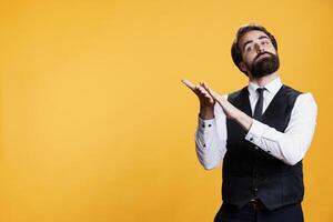 elegante experto hombre aplaudiendo alguien en cámara, aplausos manos a animar para persona en estudio. contento positivo camarero sensación optimista molesto a aumentar confianza después éxito. foto