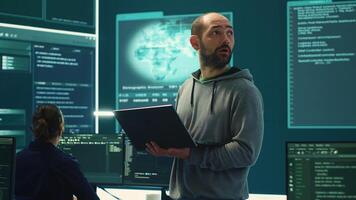 Governmental hackers breaching network security with advanced techniques, cyber defense in action. Team of IT experts working on gaining access to collect information, big screen. Camera A. photo
