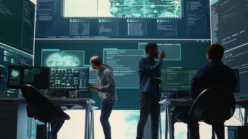 Governmental hackers analyzing cyber threats on big screens, managing important database hacking activity in high tech agency office. Work on cyber defense to protect national security. Camera B. photo
