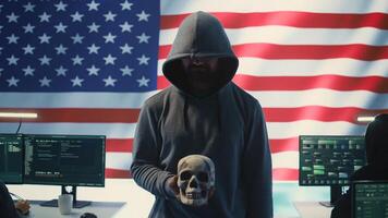 American man in a dark hood making death threats with human skull concept, emphasizing violence and malicious intent. Governmental hacker inflicting terror and panic for rival ideologies. Camera B. photo