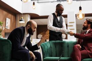 Middle eastern man on videocall in reception lobby, using online connection to meet with manager while he is travelling for work. Business representative chats on teleconference call. photo