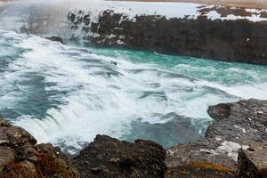 Iceland gullfoss cascade impressive river flow surrounded by snowy slopes and wildlife. Amazing massive streams of water forming cascade and famous nordic landscape in Europe. photo