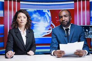 Diverse broadcasters doing reportage live on television channel, hosting morning show in media studio. Team of news presenters discussing about latest interest topics with information from headlines. photo