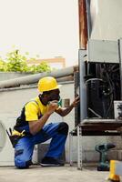 Knowledgeable professional commissioned for routine condenser cleaning, using dusting brush to clean dirty, clogged air filter decreasing efficiency and reducing unit ability to cool air effectively photo
