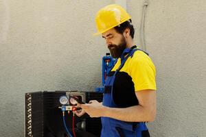 Adept repairman ordering new components for busted air conditioner after finishing servicing. Proficient worker looking online for condenser replacement parts, hired by business owner photo