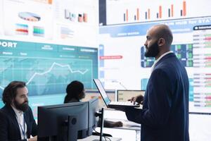 Teammates and manager assembling in a big data room to go over their results, examining graphic representations with feedback from shareholders investors. Exchanging perspectives. photo