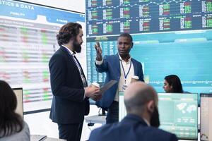 Pleased general director and investor showing statistics data to the team, proud of their organizational activity. Manager assembles with coworkers for a briefing meeting, studying sales reports. photo