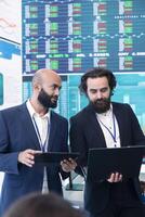 Diverse group of business specialists solve their daily tasks in control room with big screen, analyzing data numbers to ensure organizational progress. Startup management team. photo