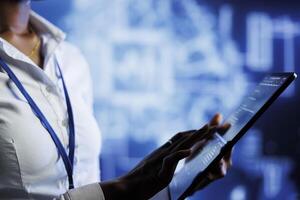 BIPOC computer operator writes code on tablet to visualize artificial intelligence neural networks using augmented reality. High tech workplace executive runs AI script for information processing photo