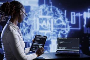 Computer scientist updates neural networks made of interconnected nodes, writing intricate binary code scripts on tablet and laptop. Server room expert uses programming to upgrade AI simulation model photo