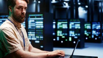 Skilled IT programmer imputing high tech facility hub disaster recovery plan on laptop to provide smooth restoration of service, limiting damage and maximizing operations uptime photo