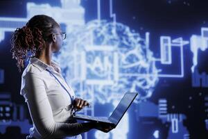IT consultant uses laptop to develop artificial intelligence neural networks nodes modeled after human brain. Server room worker setting up AI machine learning accurately making predictions using data photo