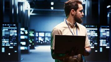 Supervisor using laptop to oversee energy consumption across server hub components and distributors. Serviceman ensuring high tech facility sensors for temperature and humidity are working properly photo