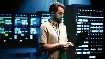 Precise serviceman verifying functional blade servers in computer network security data center. High tech facility infrastructure providing processing and memory resources for numerous workloads photo