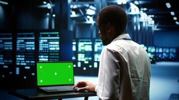 Professional examining server cabinets performance trends. Repairman using chroma key laptop to pinpoint data center operational issues arising due to high CPU usage and insufficient memory photo